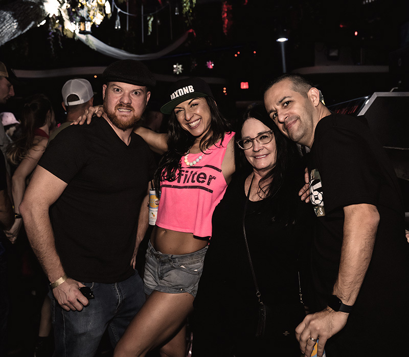 four people posing for a photo in a nightclub